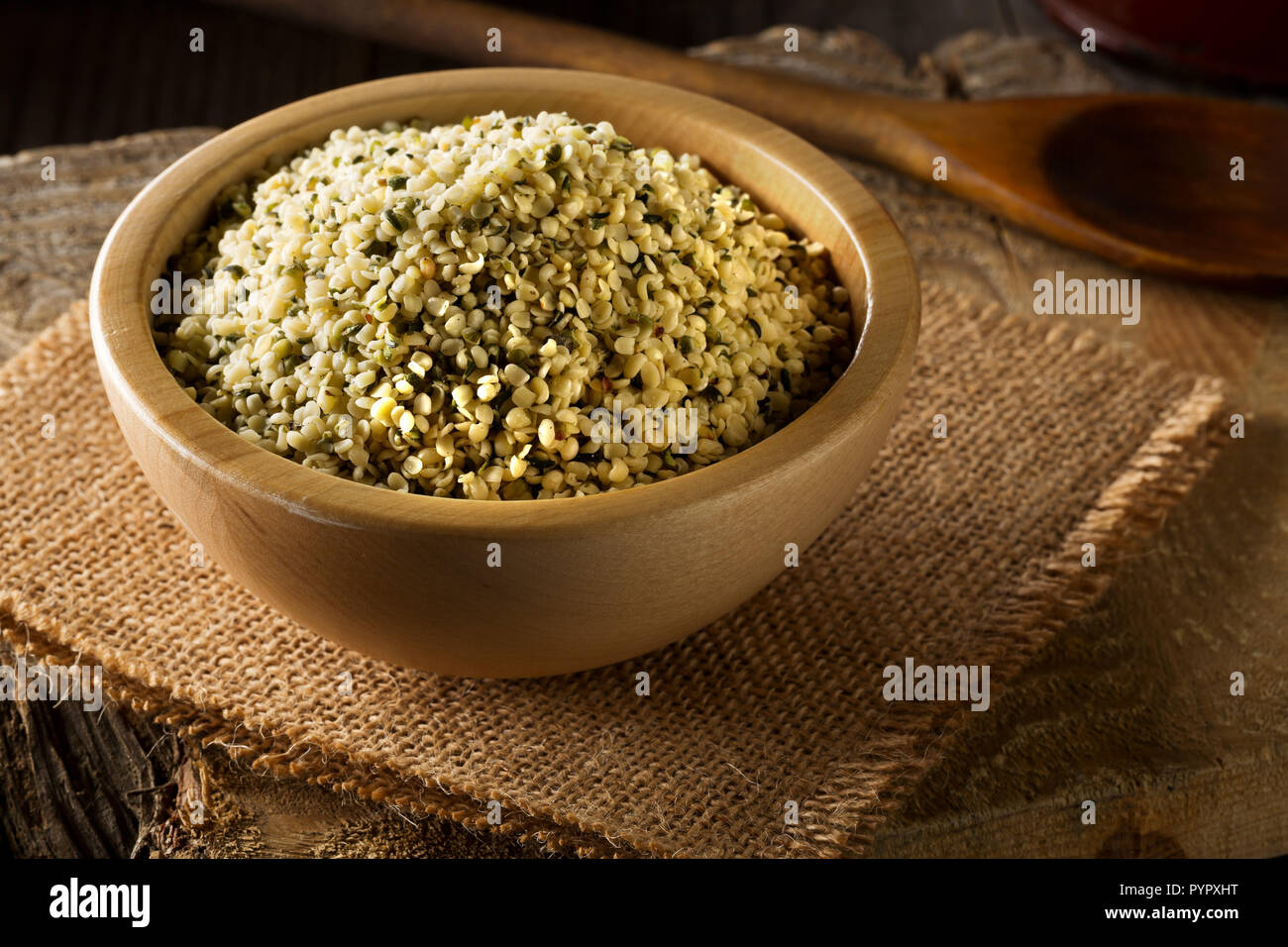 Cumulo di materie organiche di semi di canapa in ciotola di legno su tela sul tavolo rustico sfondo Foto Stock