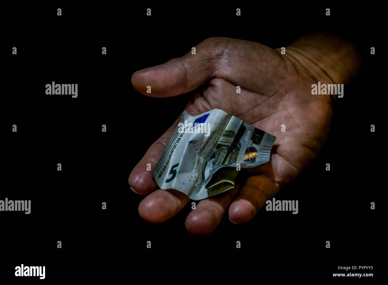 Spiegazzati cinque euro bill in mano di una persona isolata su nero. Concetto di accattonaggio per lasciare, povero piccolo salariale, donazioni. Foto Stock