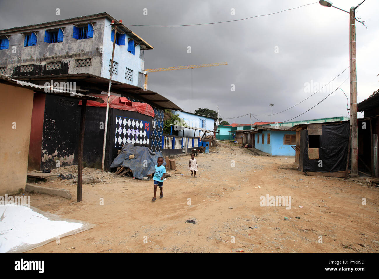 Un ragazzo e una ragazza correre giù per una strada di sporco prima di una tempesta di pioggia in Blockhauss, Abidjan, Costa d'Avorio Foto Stock