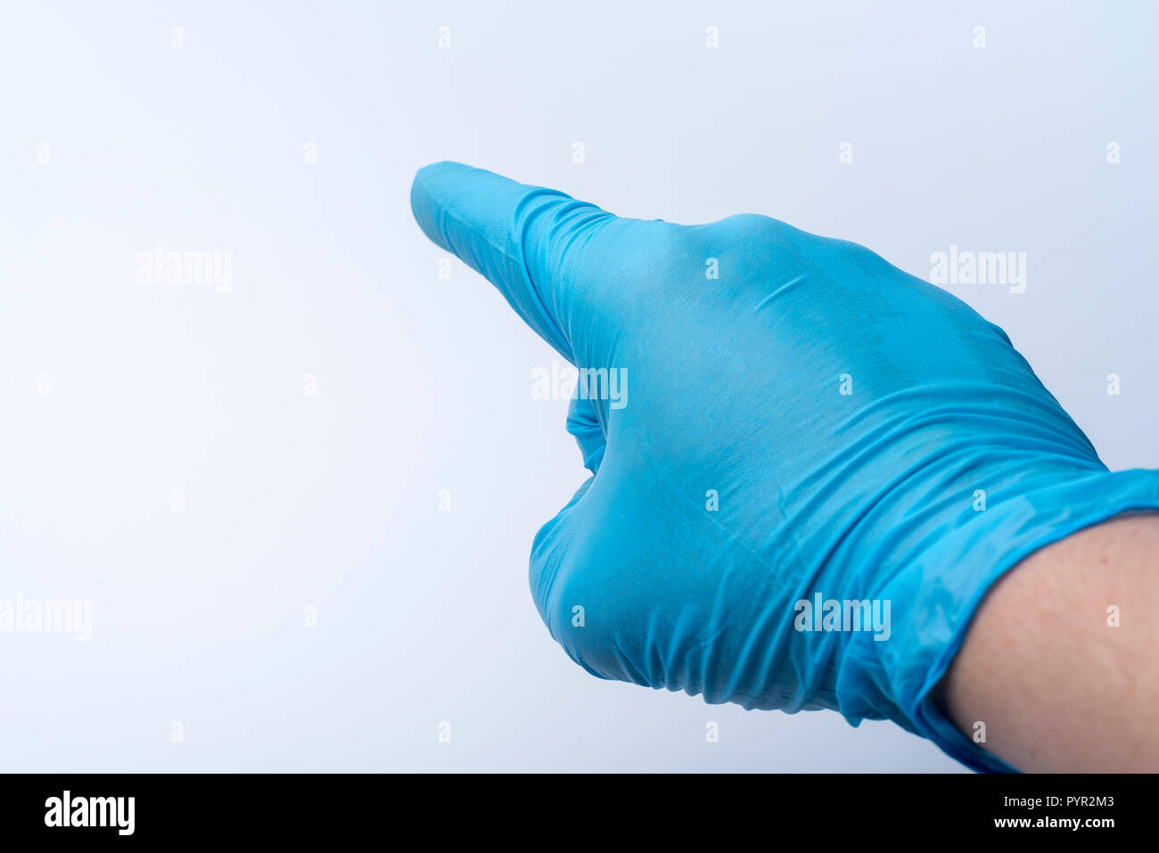 La mano guantata punti con il dito indice. Un blu guanto in lattice al dottore la mano. Foto Stock