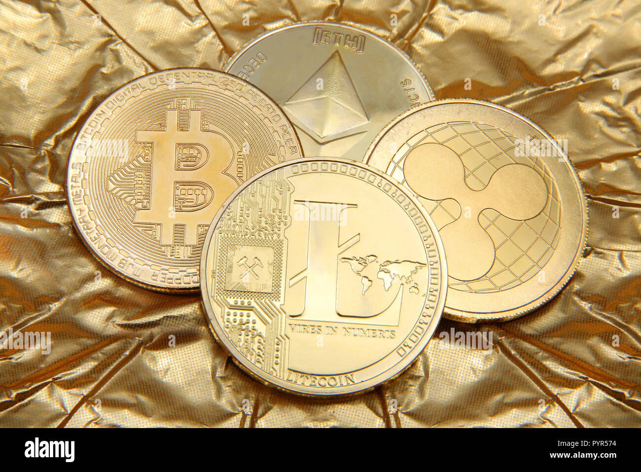 Litecoin, Ripple, Ethereum & Bitcoin golden monete raffiguranti cryptocurrenies contro un fondo oro. Foto Stock