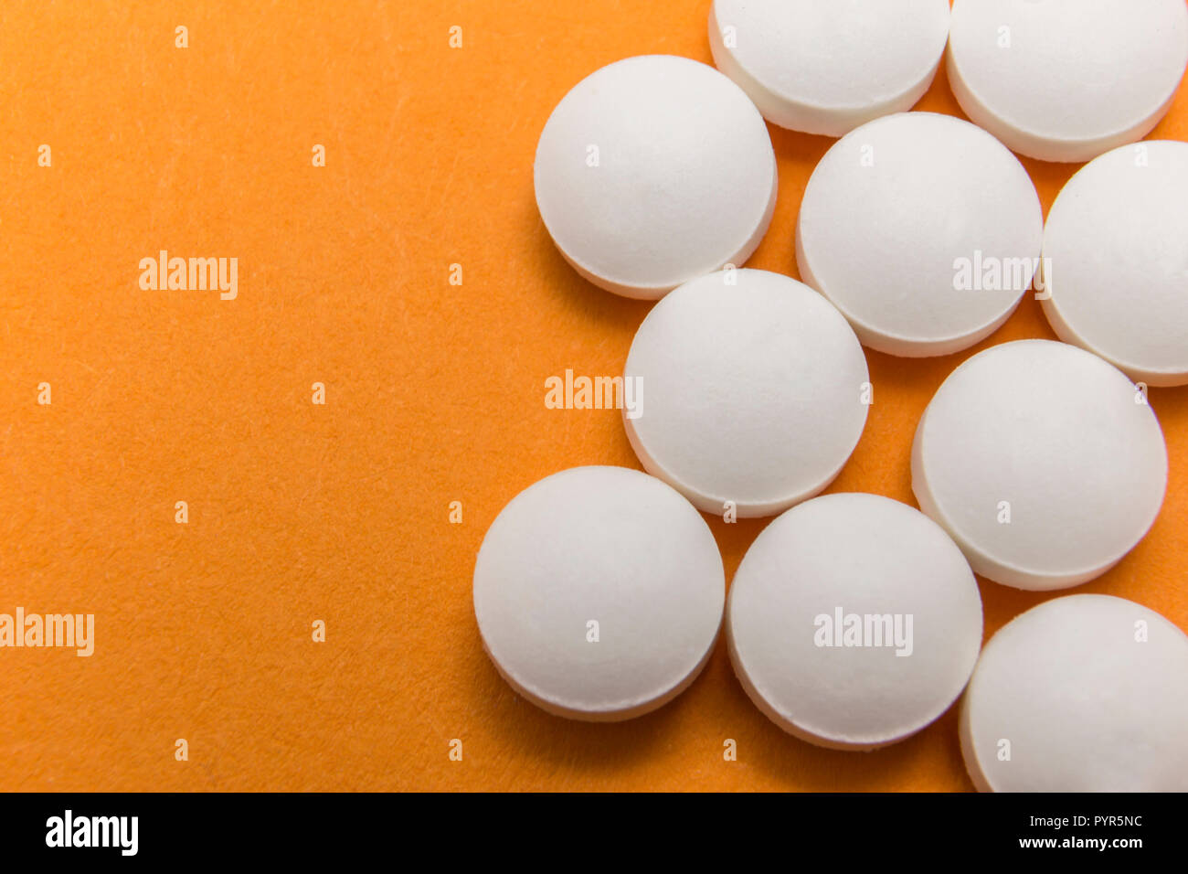Più pillole allineati bianco isolato su sfondo arancione Foto Stock