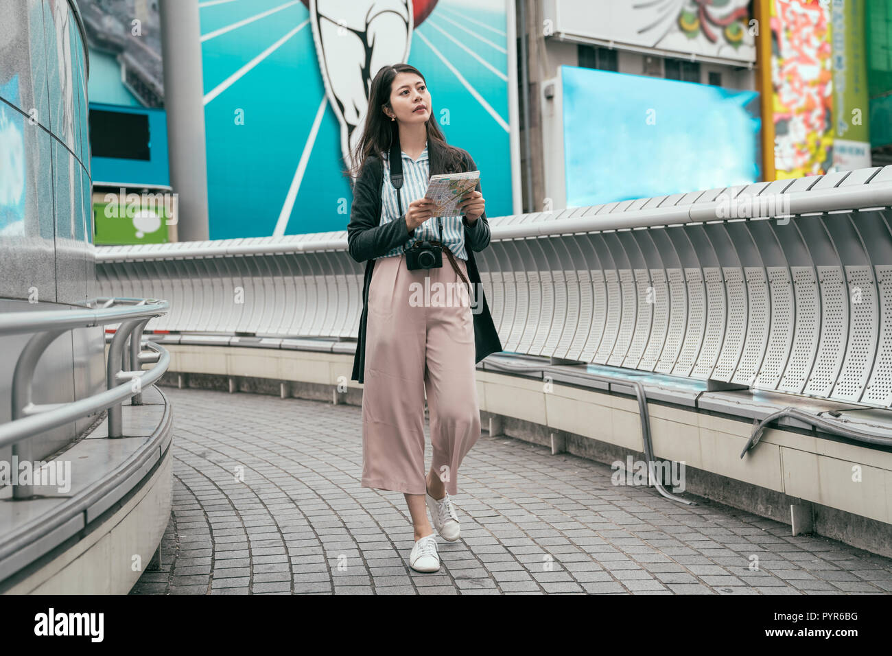 Lunghezza completa giovane lady traveler rilassanti passeggiate sul ponte con mappa. bella signora azienda mappa su carta cercando la strada per la successiva sightse di Osaka Foto Stock