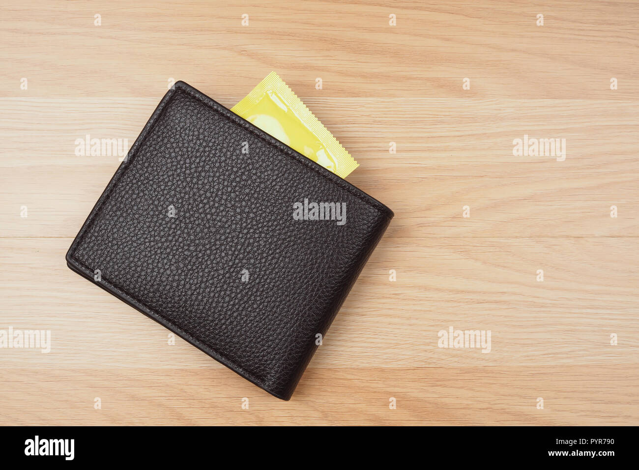 Giallo preservativi in portafoglio nero sul tavolo di legno sfondo Foto Stock