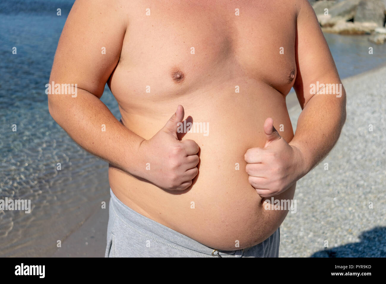 Fat Man è in appoggio e di godersi il sole sulla spiaggia Foto Stock