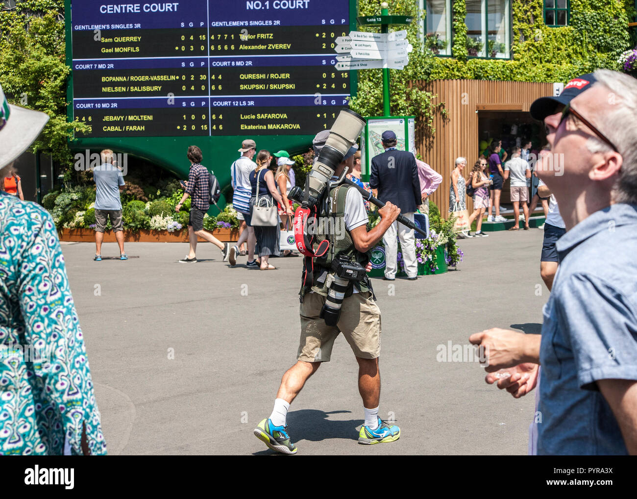 Fotografo sportivo con telecamere a piedi passato Wimbledon Tennis Championship ordine di gioco bacheca Foto Stock