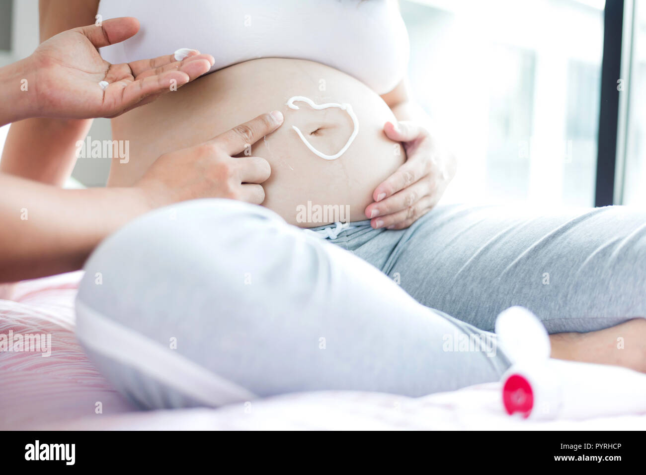 Asian donna incinta con grande pancia. Rilassarsi a casa con il marito. Foto Stock