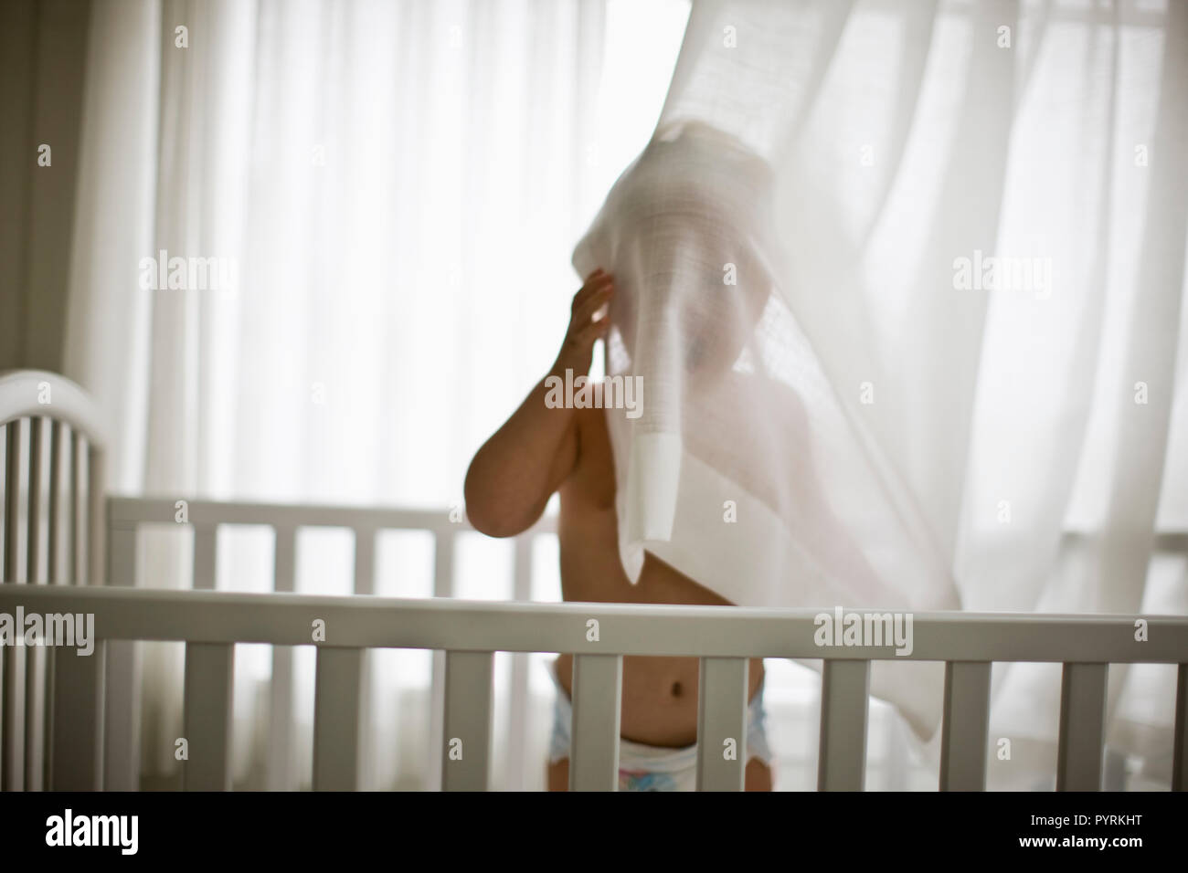 Il Toddler boy in piedi nel presepe e nascondersi dietro la cortina Foto Stock