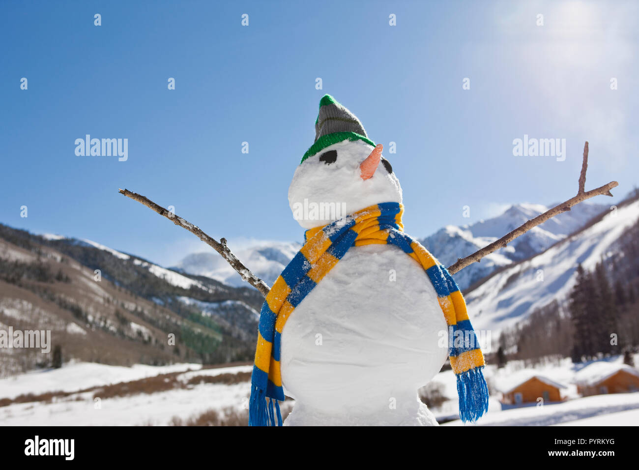 Pupazzo di neve indossando s sciarpa a righe un berretto lavorato a maglia in un paesaggio invernale. Foto Stock