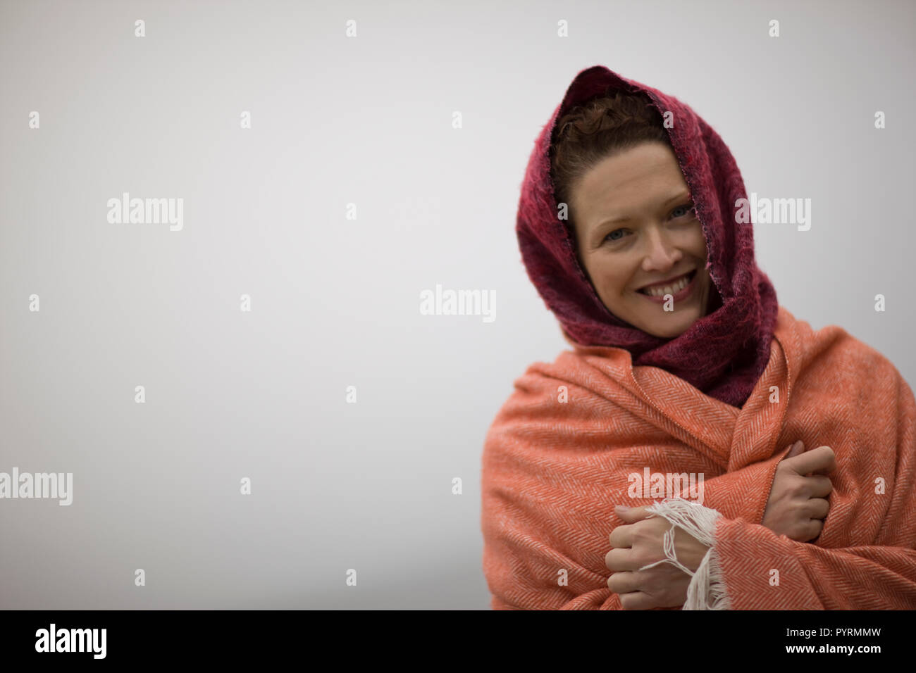 Ritratto di una donna sorridente avvolto in coperte. Foto Stock