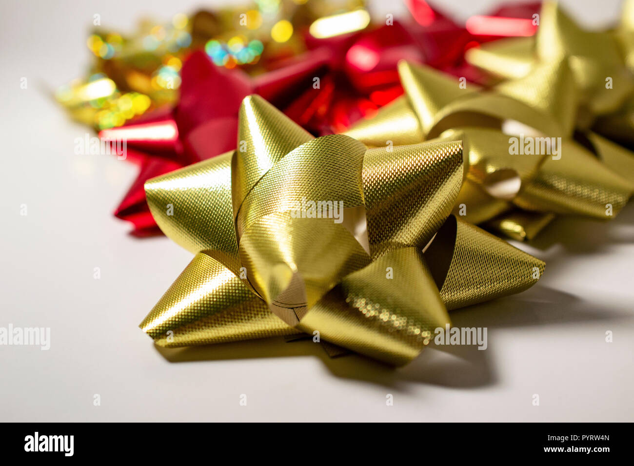 Vacanze di Natale la confezione regalo nastro di raso archi. Oro, oro e rosso. Camera per copia. La luce bianca dello sfondo. Foto Stock