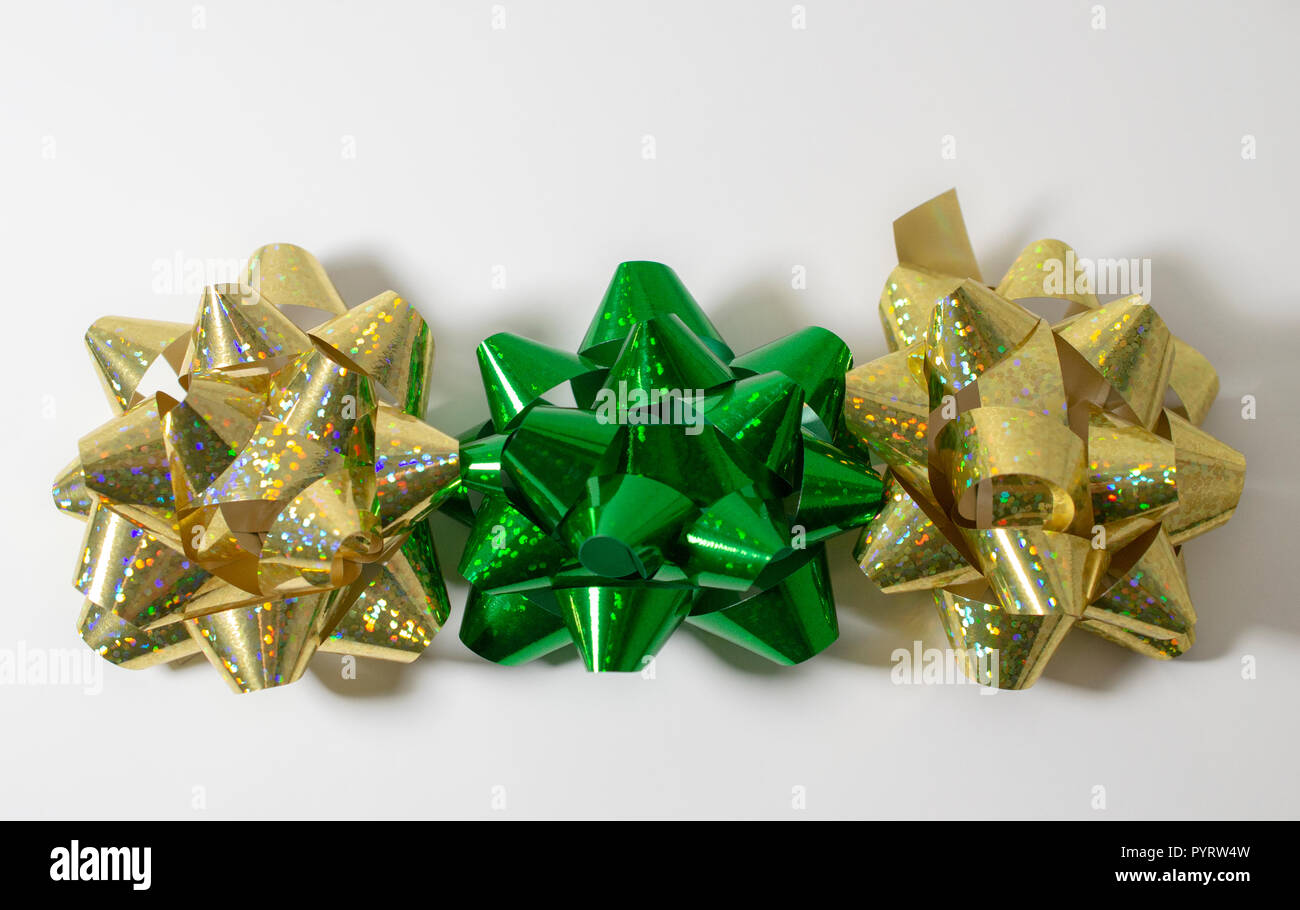 Vacanze di Natale la confezione regalo archi 2 oro e 1 verde. La luce sullo sfondo bianco. Un sacco di spazio per la copia. Colori brillanti. Foto Stock