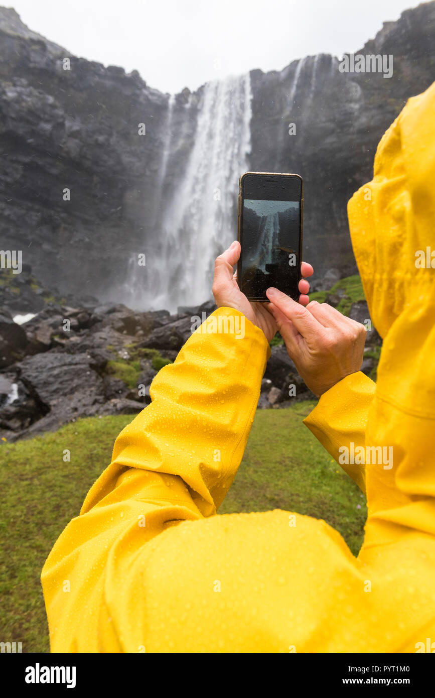 Tourist scatta le foto con lo smartphone, Fossa cascata, Streymoy isola, isole Faerøer, Danimarca Foto Stock