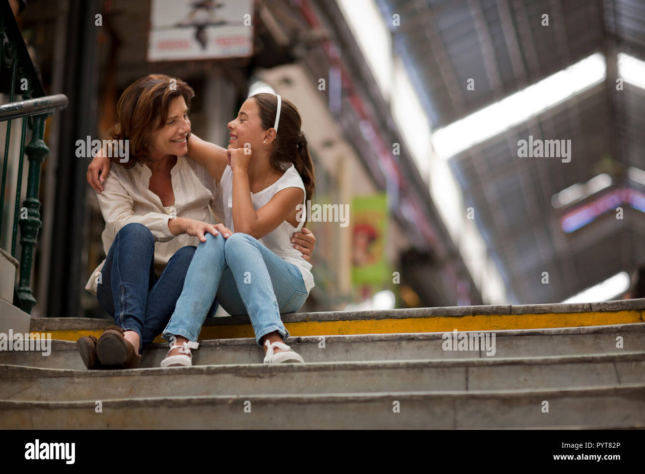 Senior donna e suo nipote con le loro braccia intorno a vicenda mentre è seduto alla parte superiore di una rampa di scale. Foto Stock