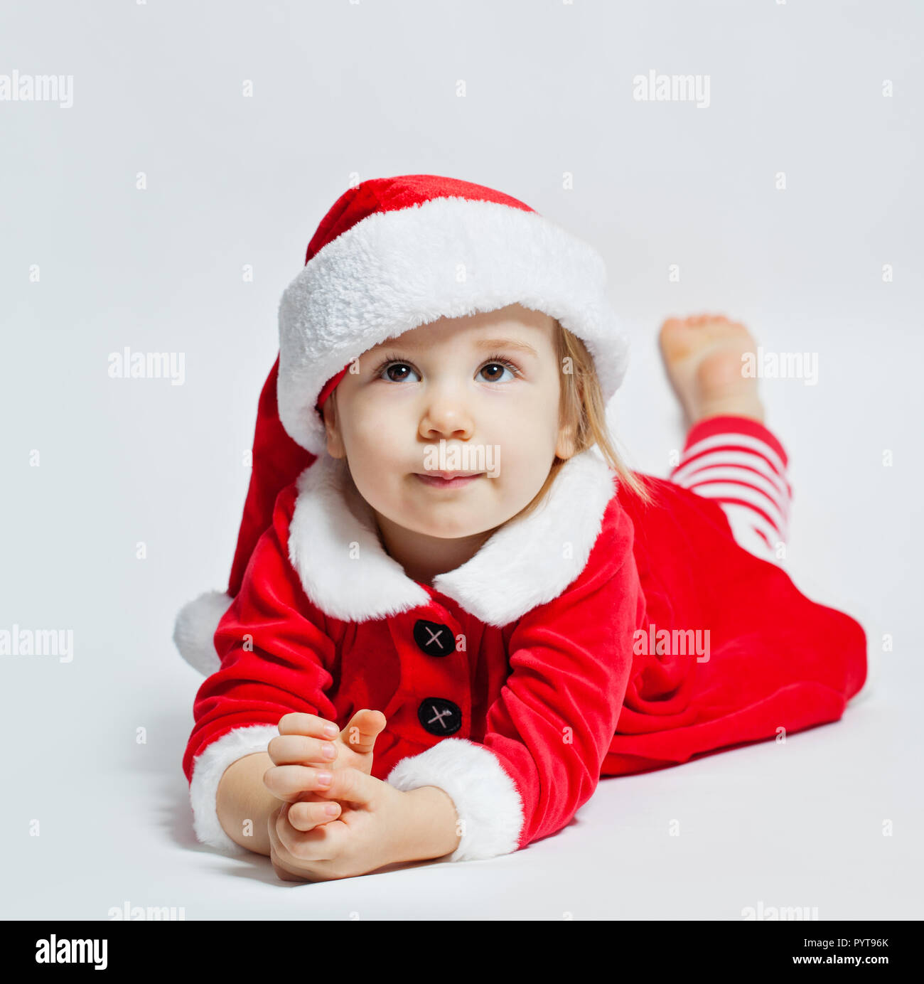 Natale bambino in Santa hat guardando verso l'alto e sognare il regalo di Natale su sfondo bianco Foto Stock