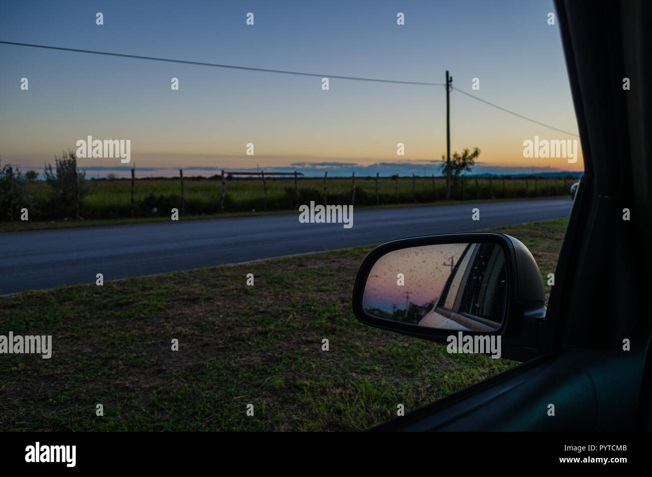 Strada dall'interno di una vettura e la riflessione del retrovisore della vettura. viaggio al tramonto, bel tramonto dall'interno di un'auto. Foto Stock