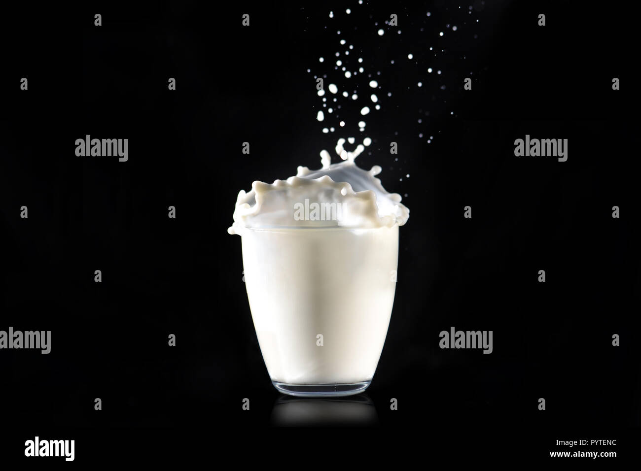 Gli spruzzi di latte sono come un cappello fatto di vetro trasparente in vetro su uno sfondo nero. Foto Stock