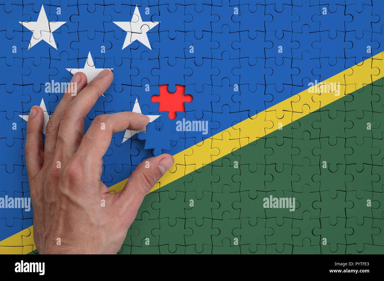 Isole Salomone bandiera è rappresentato su un puzzle che la mano dell'uomo completa per la piegatura. Foto Stock