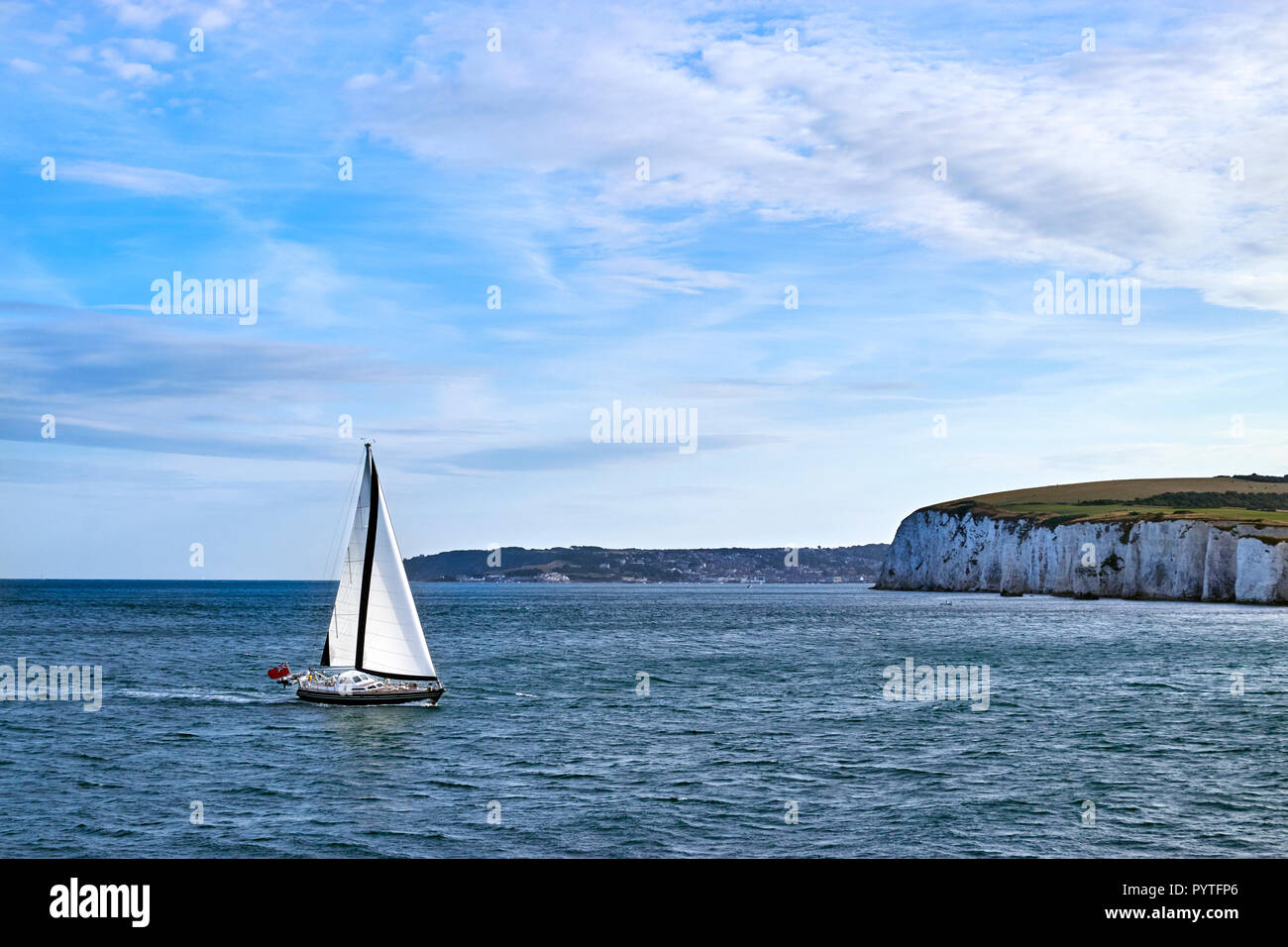 Sailing yacht a vela nel Canale della Manica fuori le bianche scogliere in acqua calma con il cielo azzurro e qualche nuvola. Foto Stock