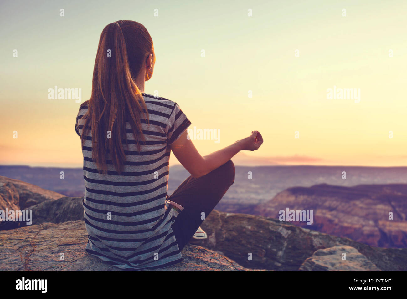 Una ragazza sulla cima di una collina nel silenzio e nella solitudine si ammira un tranquillo paesaggio naturale in cerca di un'anima. O lei le pratiche yoga e meditazione. Foto Stock