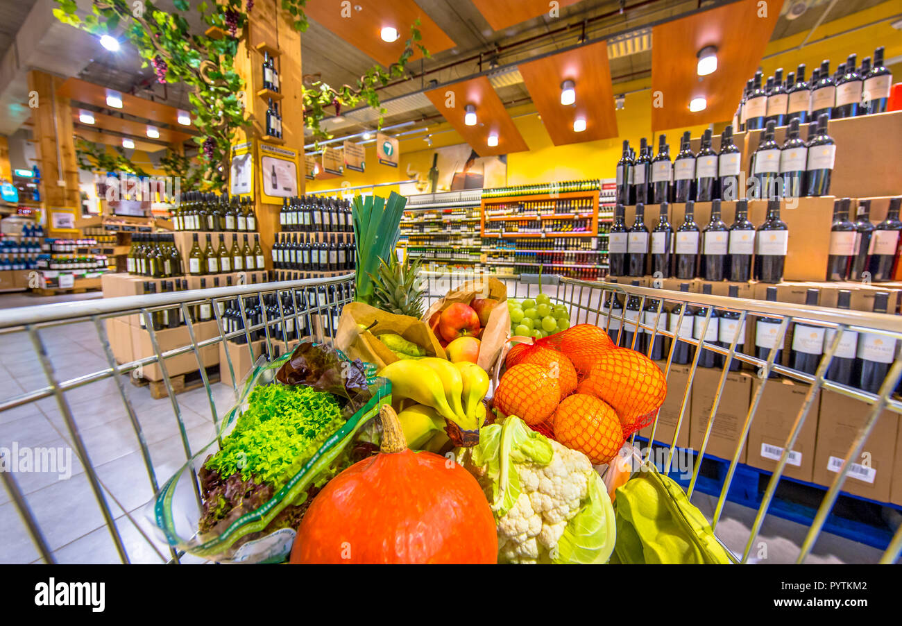 Negozio di alimentari carrello nel supermercato riempito con sani e freschi prodotti alimentari sul vino e alcole sezione come concetto per la forza di volontà e malsano Foto Stock