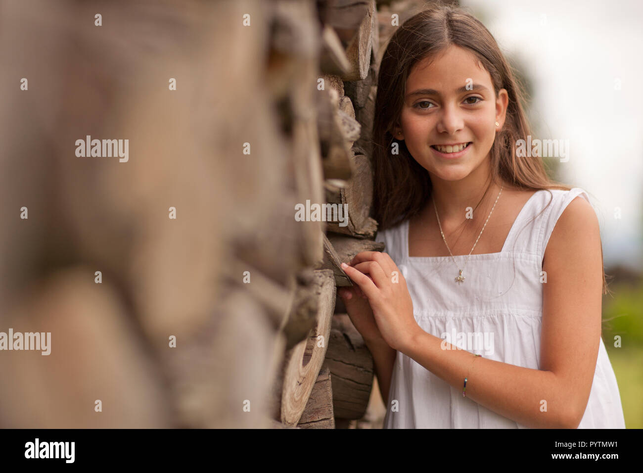 Ragazza sorridente appoggiato sulla recinzione di log. Foto Stock