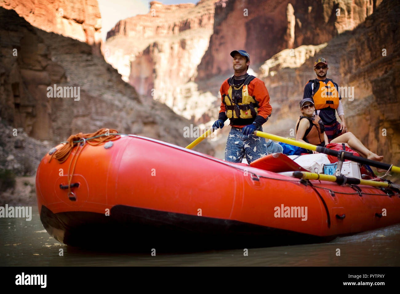 Gruppo sorridente di amici divertendosi mentre rafting insieme sulle rive di un fiume in un canyon rocciosi. Foto Stock