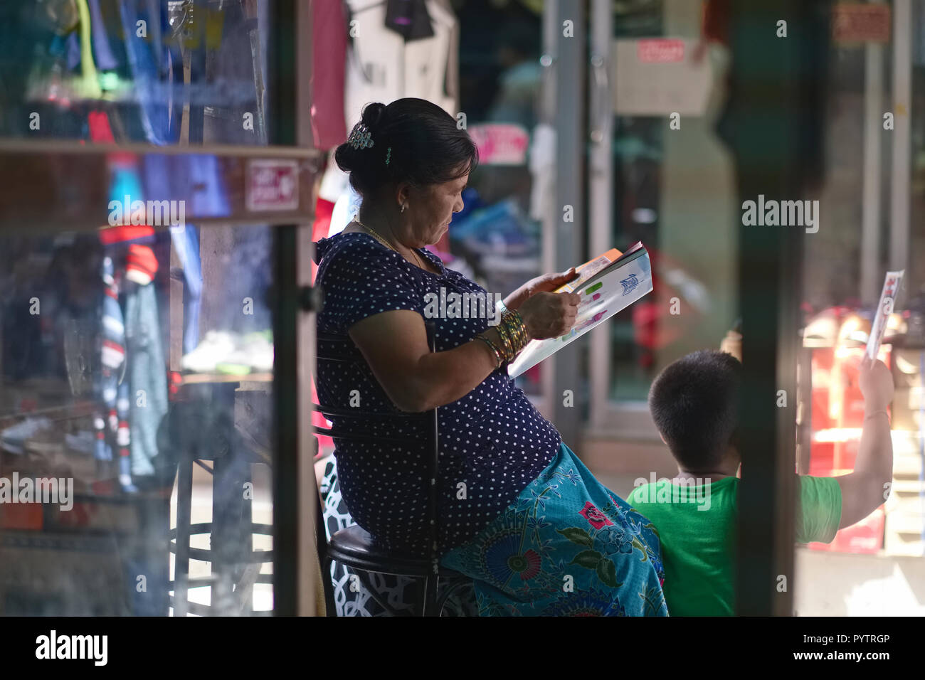 Un etnia nepalese lavoratore migrante dal Myanmar (Birmania) a Bangkok, in Thailandia, che stanno curiosando una rivista Foto Stock