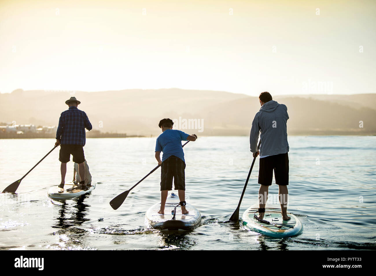 Padre paddleboarding con i suoi figli. Foto Stock