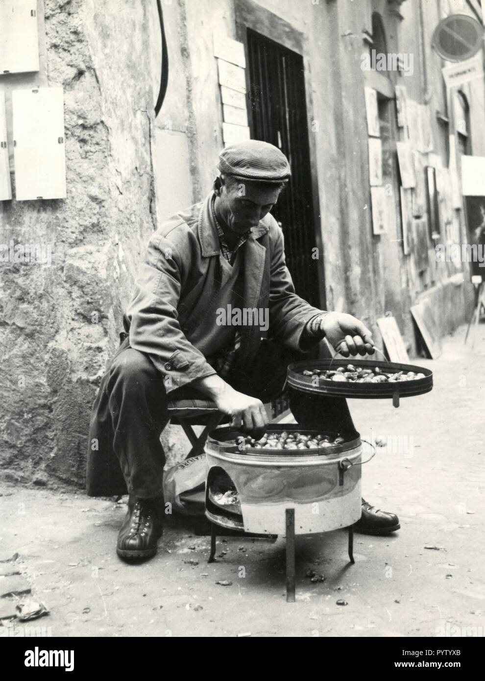 L'uomo vendita di castagne arrostite sulla strada, Roma, Italia degli anni settanta Foto Stock