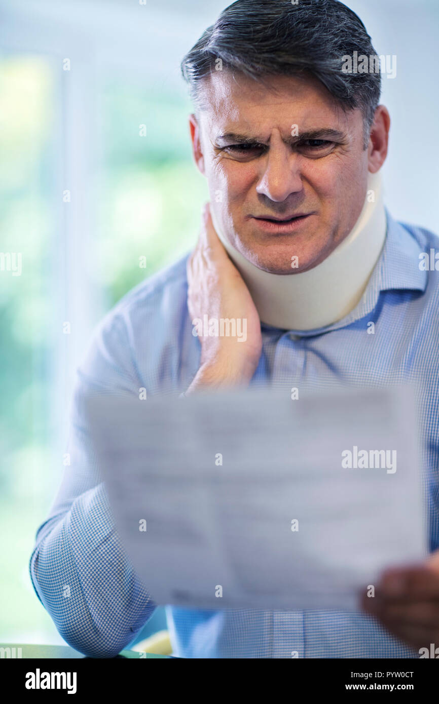 Uomo maturo lettura la lettera dopo la ricezione di lesioni al collo Foto Stock