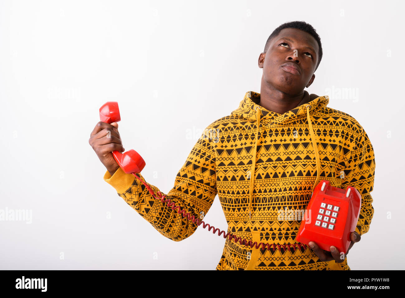 Studio shot del giovane nero africano tenendo il vecchio telefono whi Foto Stock