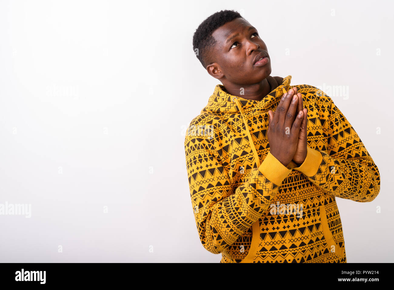 Studio shot del giovane africano nero uomo che prega mentre un pensiero Foto Stock