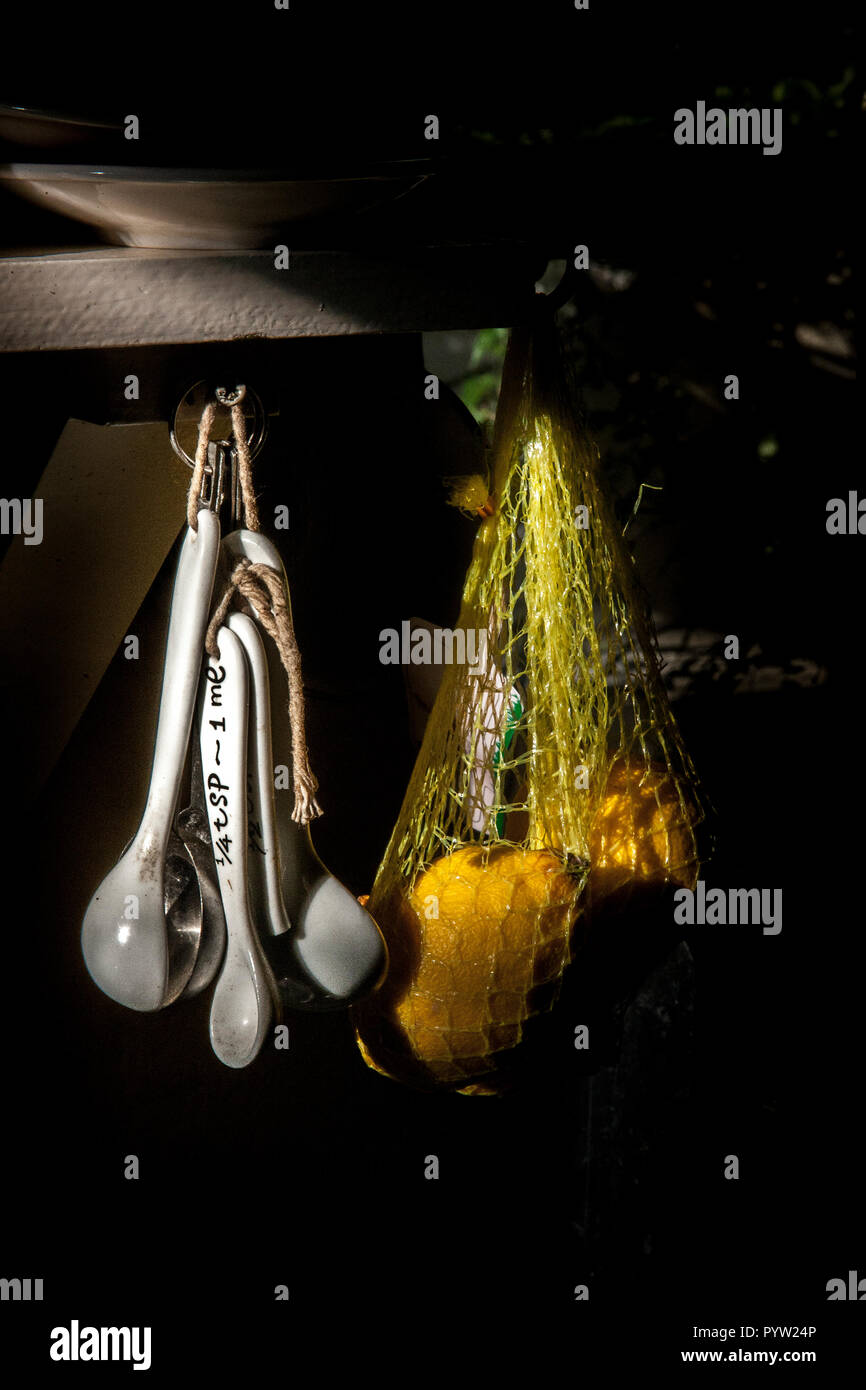 Ceramica misurini appeso accanto al sacchetto di limoni in cucina Foto Stock