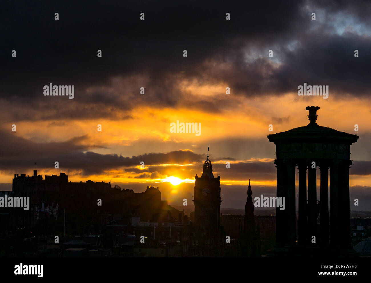 Edimburgo, Scozia, Regno Unito, 30/10/2018. Regno Unito Meteo: arancione tramonto nel centro della città con il distintivo contorni di Edimburgo di edifici e monumenti tra cui il Dugald Stewart monumento, Balmoral Hotel la Torre dell Orologio e il Castello di Edimburgo visto da di Calton Hill Foto Stock