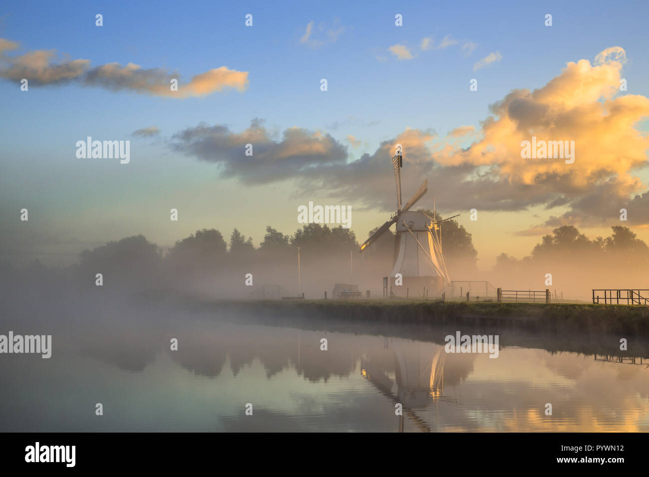 Storico di colore bianco il mulino a vento di legno nella nebbia mattutina durante il coloratissimo sunrise, Drenthe, Paesi Bassi Foto Stock