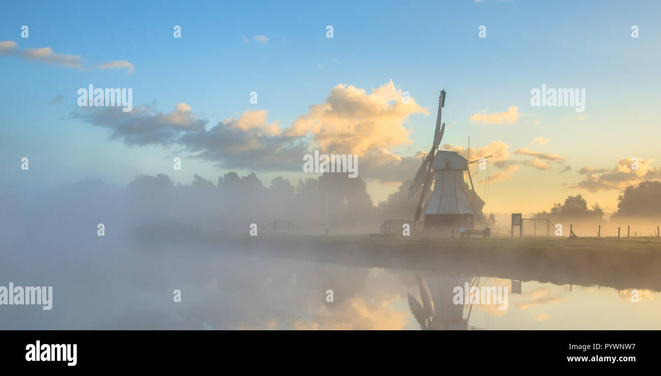 Panorama di bianco il mulino a vento di legno nella nebbia mattutina durante il Sunrise, Drenthe, Paesi Bassi Foto Stock