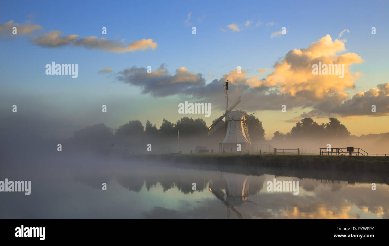 Storico mulino a vento di legno su una mattinata nebbiosa sotto calda bella sunrise, Drenthe, Paesi Bassi Foto Stock