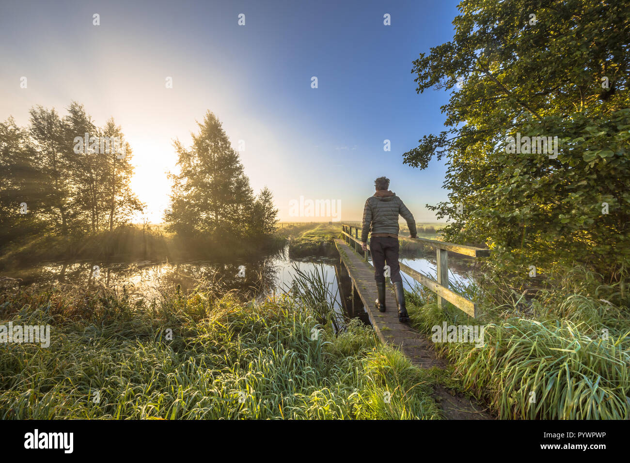 Persona che cammina attraversando ponte per l'altro lato luminoso come un concetto per affrontare un problema e una metafora per la progressione. Foto Stock