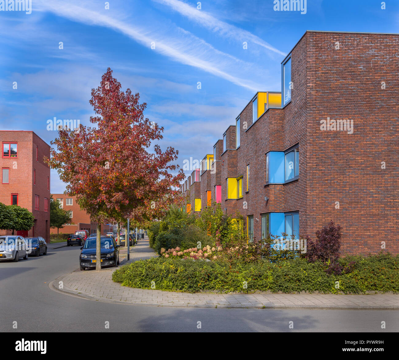 Il blocco di colorati suburbana moderni appartamenti per famiglie in un vivace quartiere corretto con alberi e giardini Foto Stock