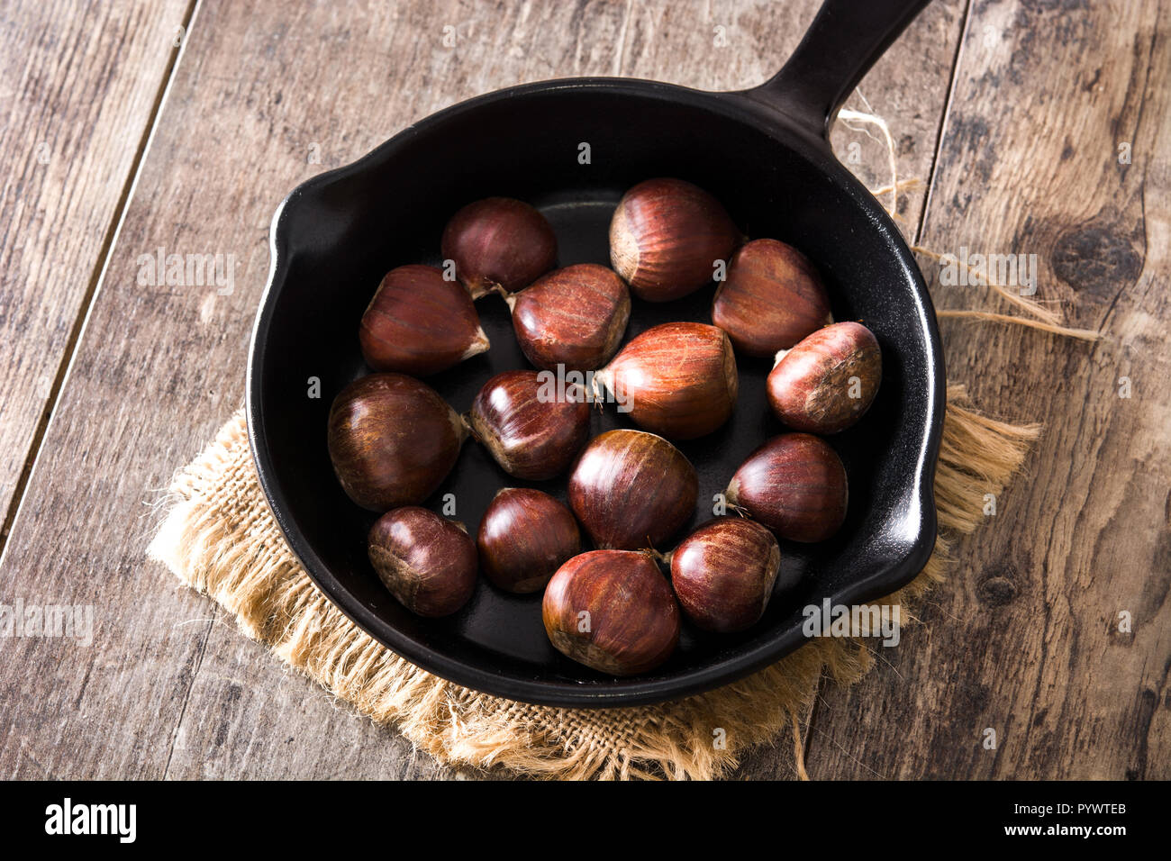 Le castagne in padella di ferro sul tavolo di legno Foto Stock