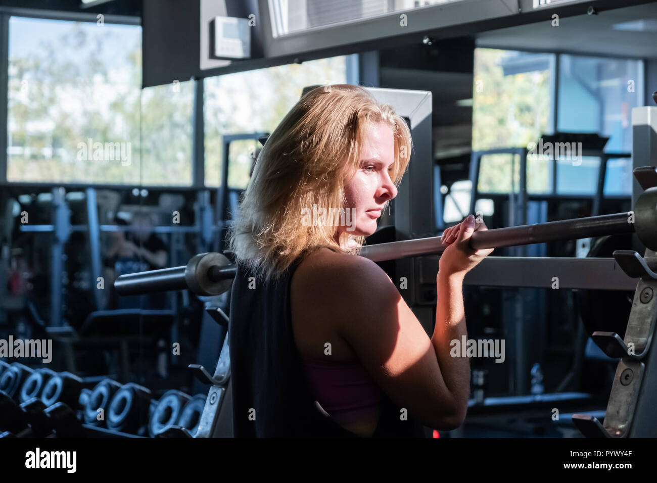 Montare la giovane donna presso la palestra facendo esercizio heavylifting. Atleta femminile in una sala fitness che lavora fuori con barbell Foto Stock