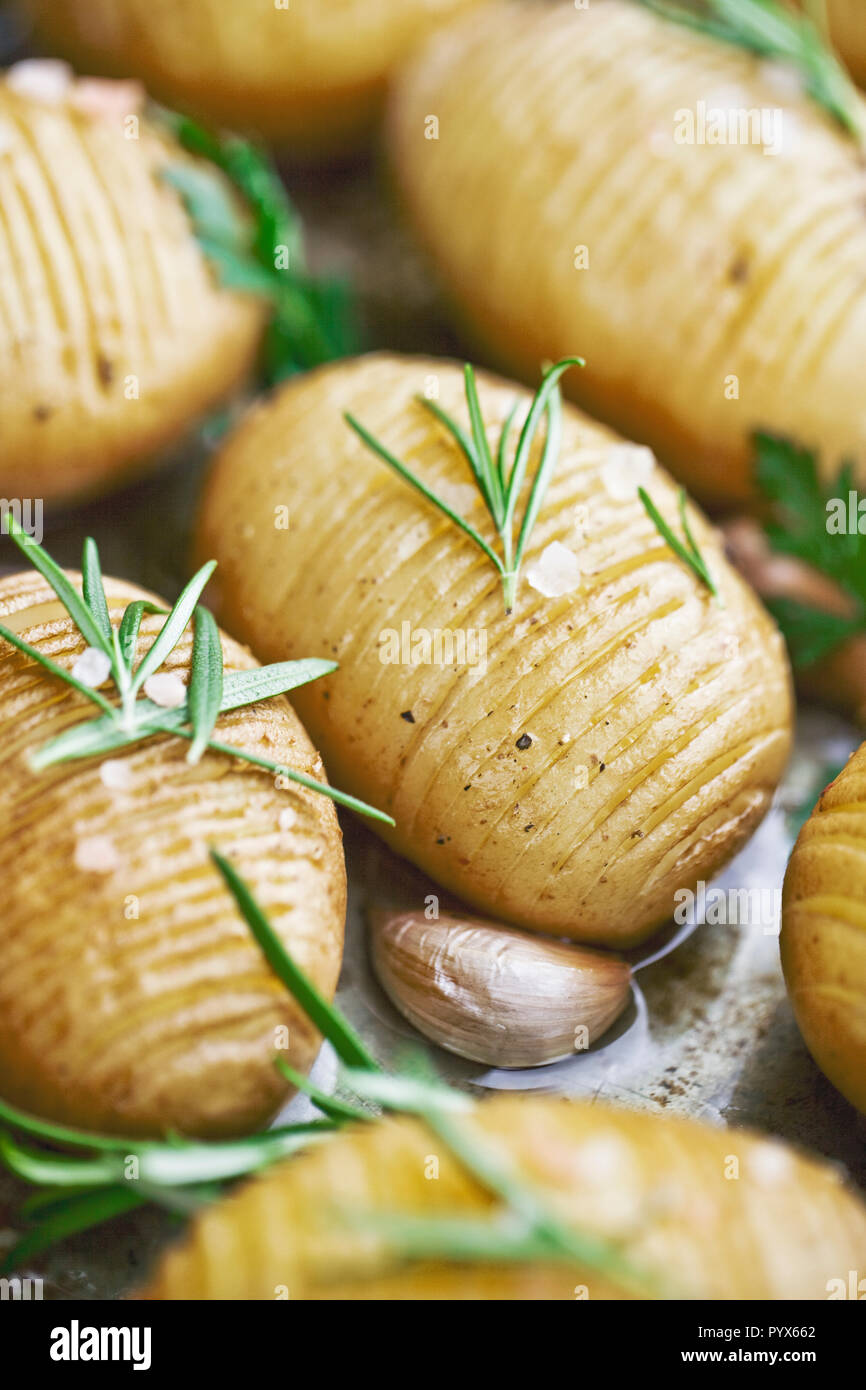 Rustico patate Hasselback con erbe aromatiche, aglio e sale, vegetariane con cibo di buona qualità Foto Stock