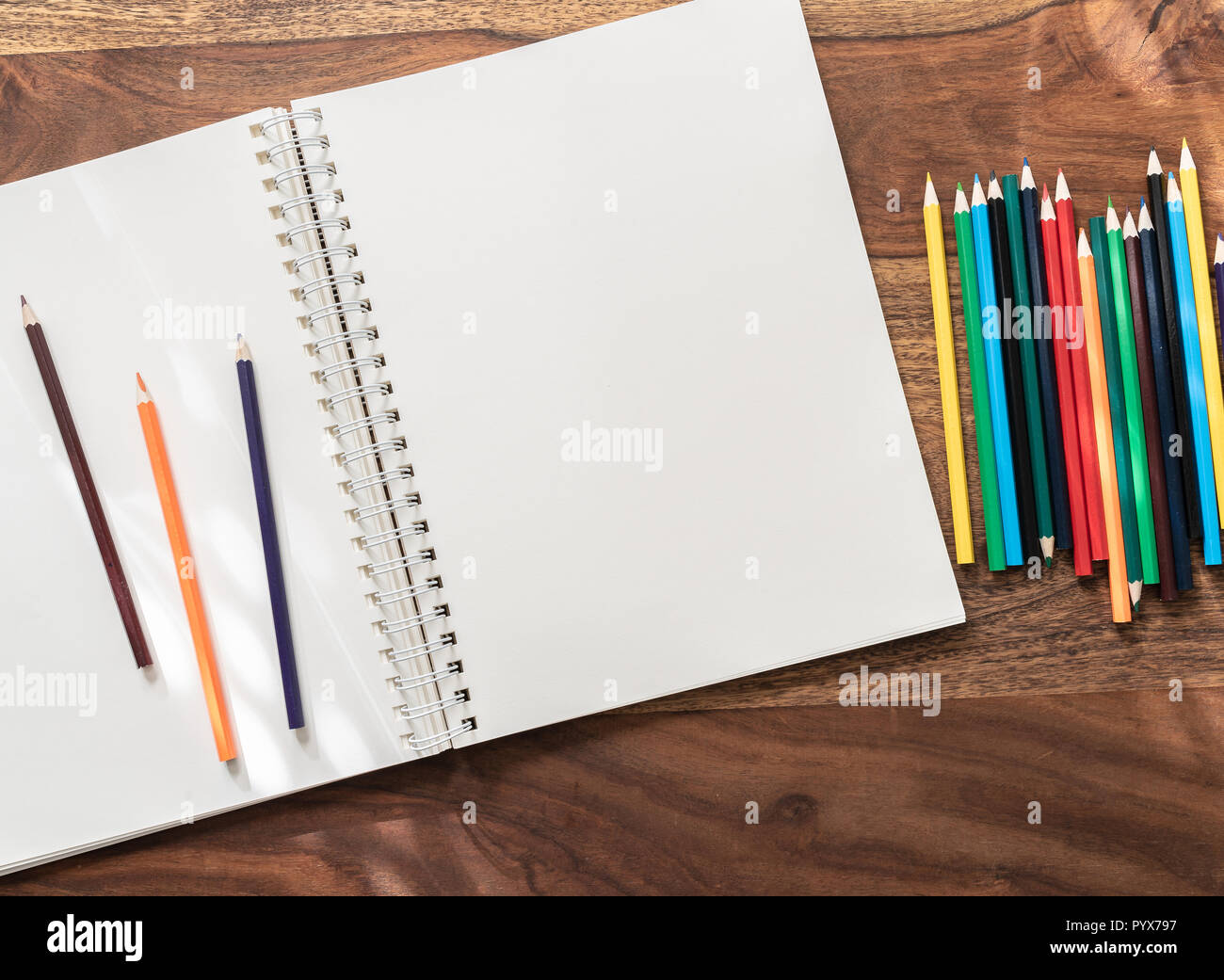 Aprire vuoti sketchbook e matite colorate su un tavolo di legno Foto Stock