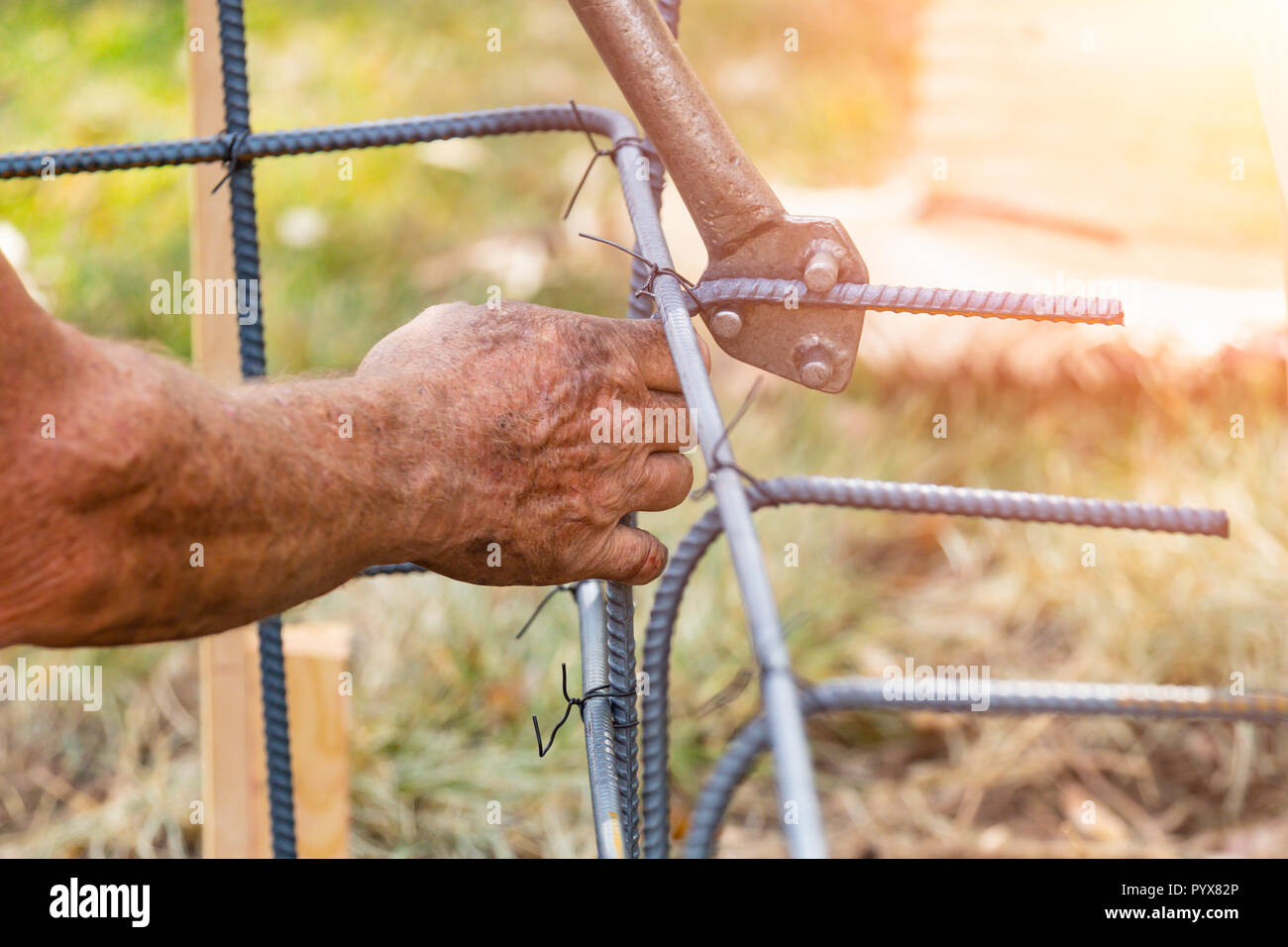 Lavoratore utilizzando strumenti di piegare tondino in acciaio al sito in costruzione. Foto Stock