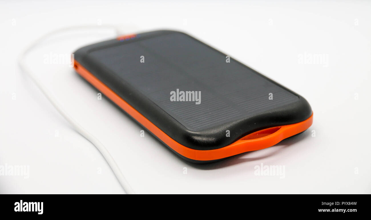 Nero/Arancio 10000mah torna con pannello solare. Cavo USB bianco ad esso collegato. Foto Stock