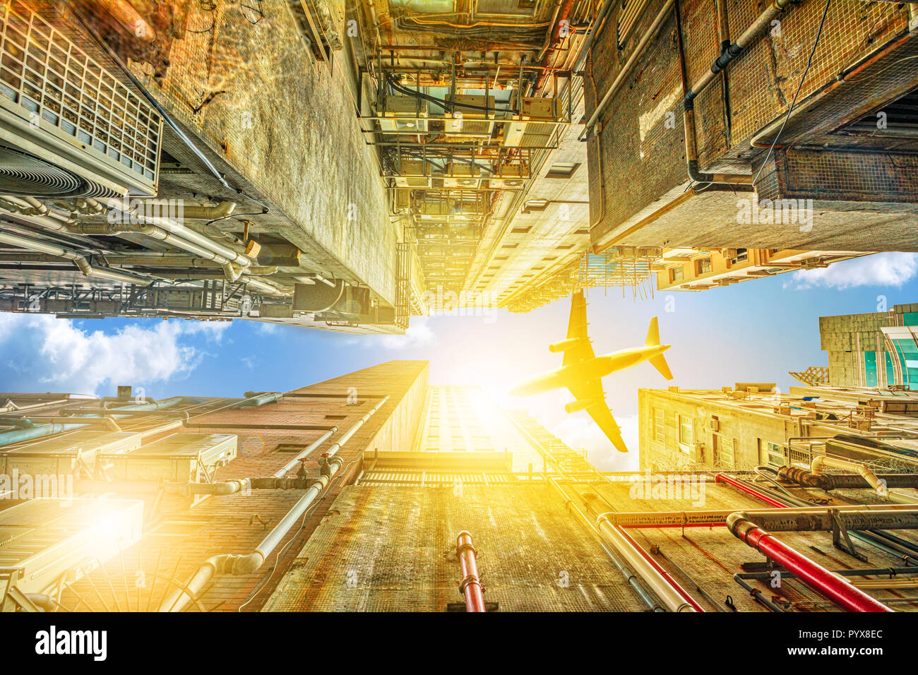 Vista dalla parte inferiore di grattacieli di aereo volando sul distretto di Kowloon a Hong Kong, Cina. Affollata costruzione urbana con luce solare del Cielo di tramonto. Foto Stock