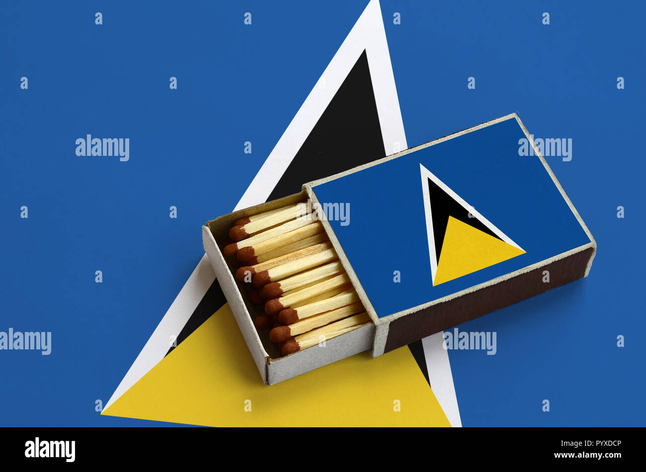 Saint Lucia flag è mostrato in un aperto la scatola di fiammiferi, il quale è riempito con corrispondenze e giace su di una bandiera di grandi dimensioni. Foto Stock