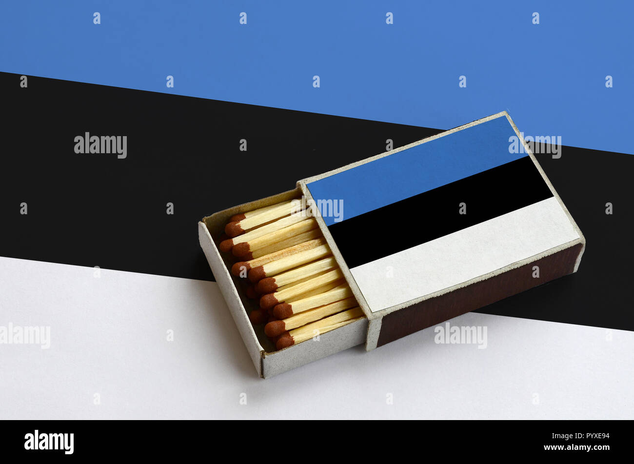 Bandiera dell'Estonia è mostrato in un aperto la scatola di fiammiferi, il quale è riempito con corrispondenze e giace su di una bandiera di grandi dimensioni. Foto Stock