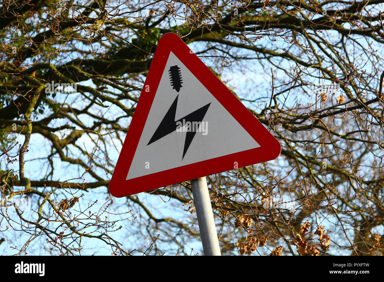 Un profilo triangolare cartello stradale di avvertimento sovraccarico delle linee elettriche di alimentazione, England, Regno Unito Foto Stock